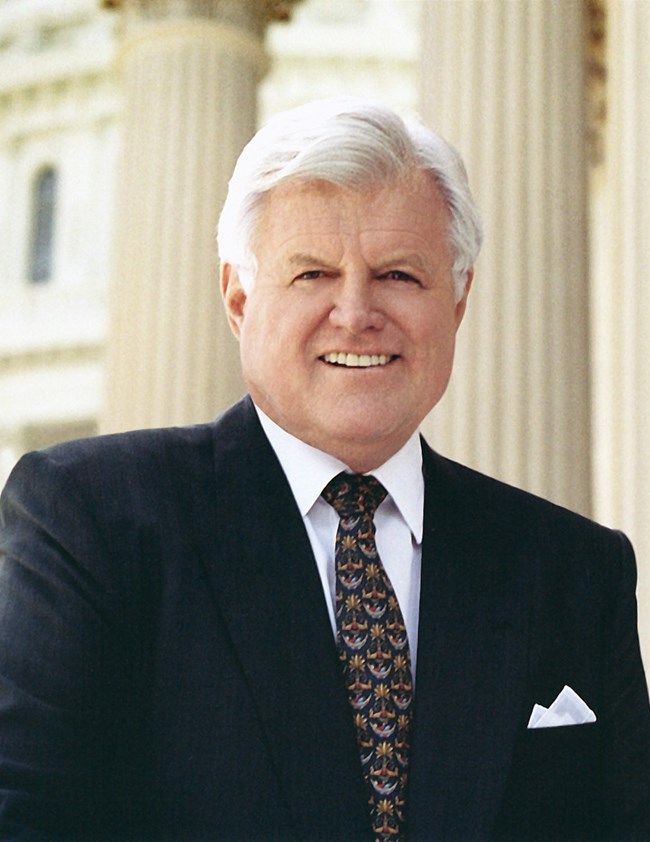 An older Ted Kennedy dressed in a dark suit.
