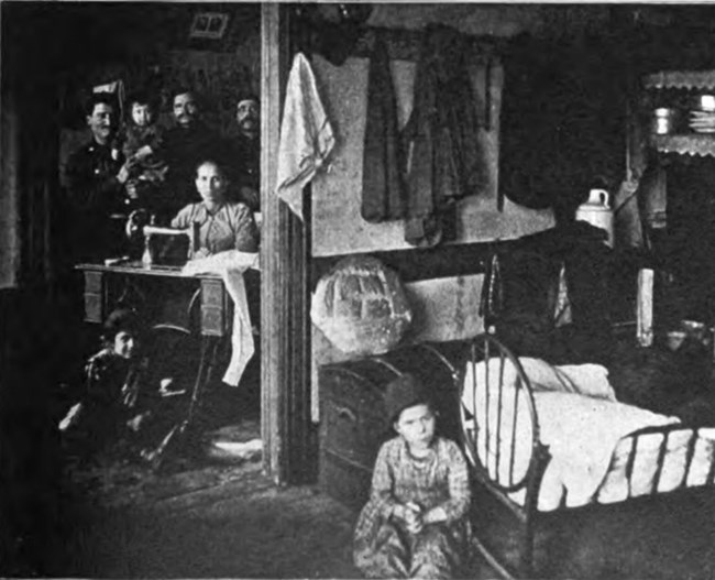 black and white photo of seven people living in a two room tenement