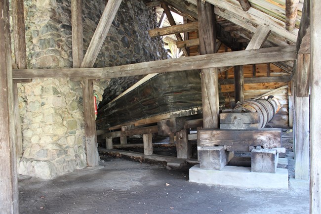 Stone wall with large air bellows and wooden wheel.