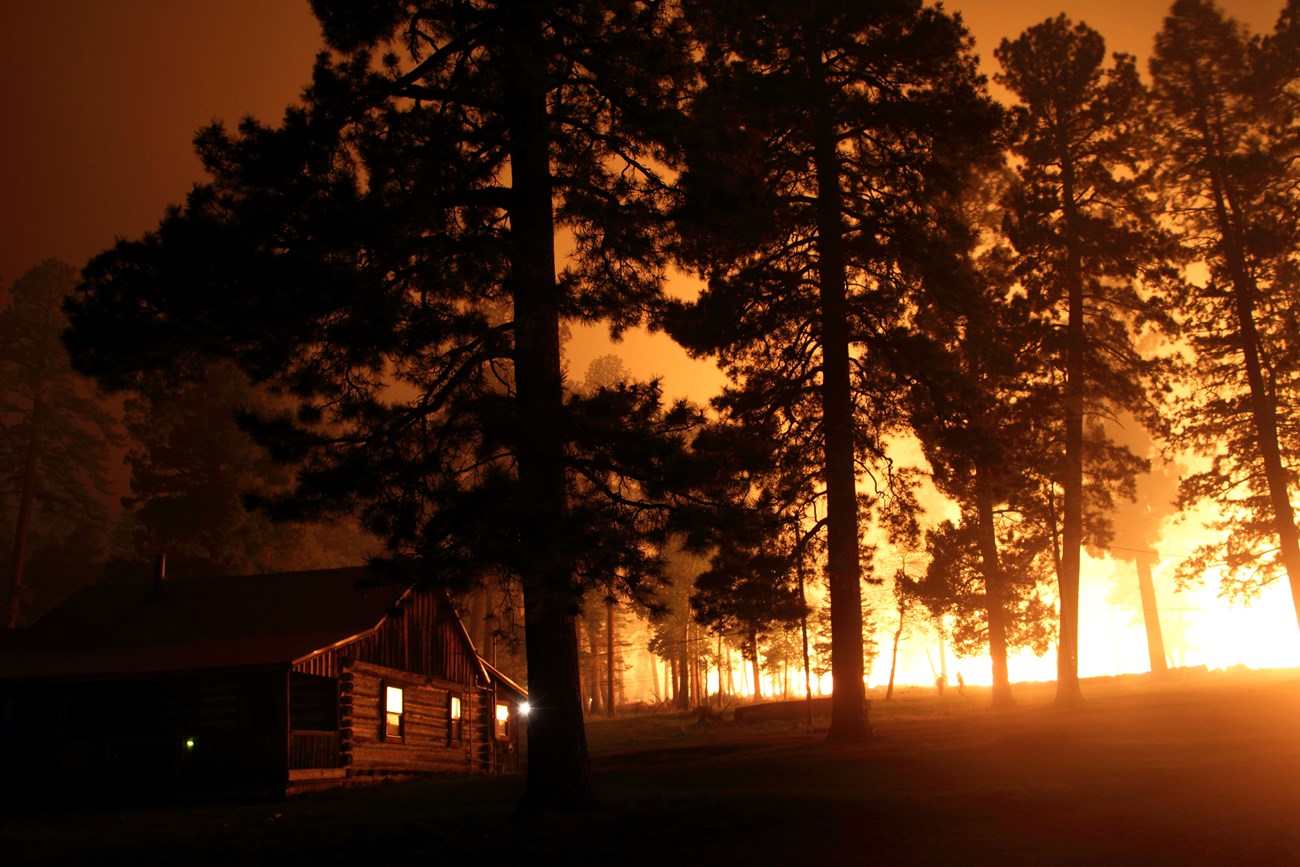 Cabin at night with fire burning behind it.