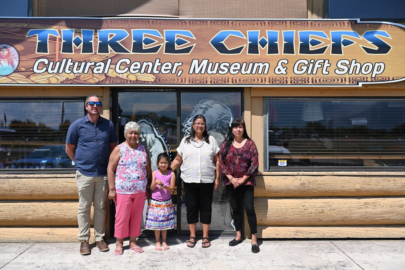 five people in front of a museum entrance sign