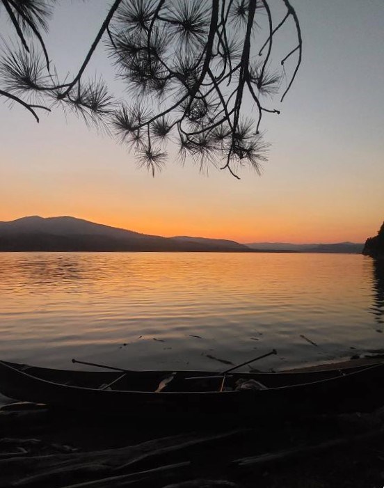 Sunset over Lake Roosevelt. Sunset glows over a lake, with a canoe sitting on the shoreline.