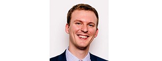 a headshot of a smiling man with brown hair