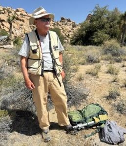Tom_Photo 1 A man is shown standing with field gear in a desert environment.
