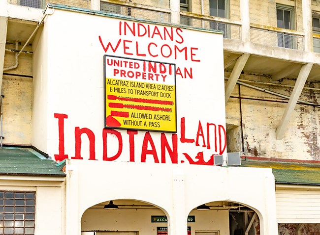 A photo of red paint graffiti on the Golden Gate NRA entrance that reads "Indians welcome in Indian Land."