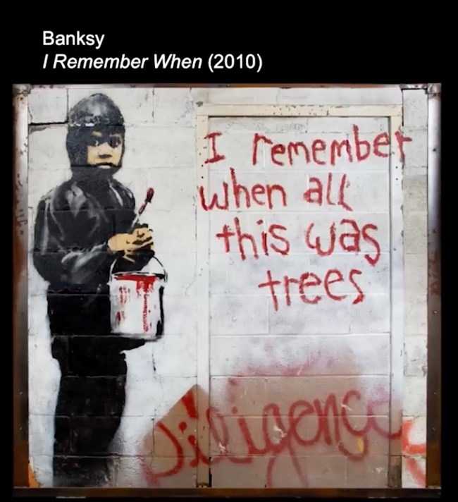 Paint on masonry of a boy with a brush and bucket of red paint who wrote "I remember when all this was trees."