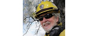 Headshot of Tony in the field with fire gear and a yellow NPS helmet.