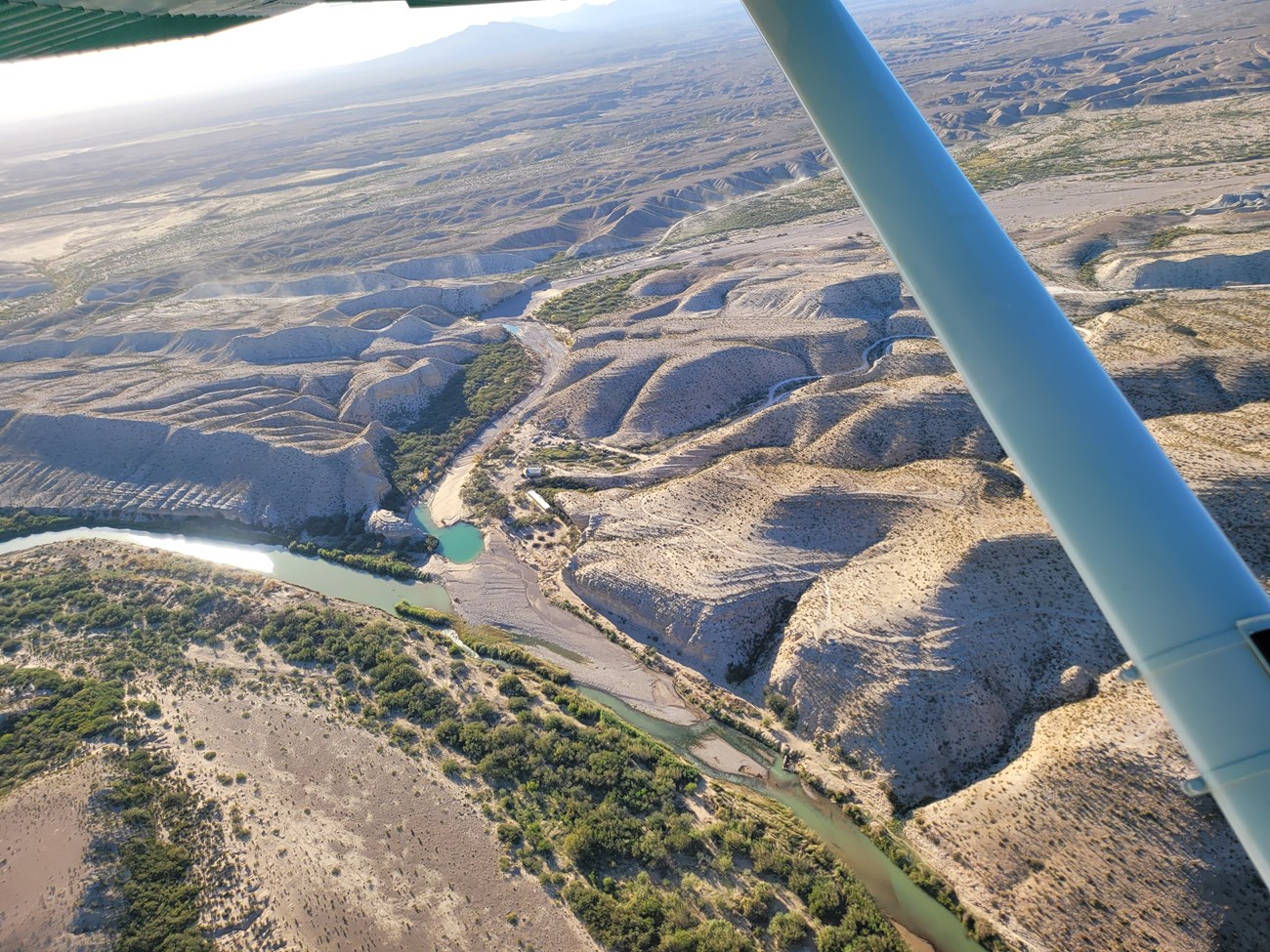 An aerial photo of the confluence of two rivers with desert foothills on either side