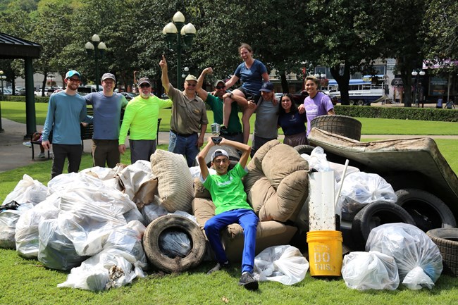 Winning group from Hot Springs:Trash Pandas A group stands among a large pile of debris smiling and celebrating, one sits among the debris holding a trophy.