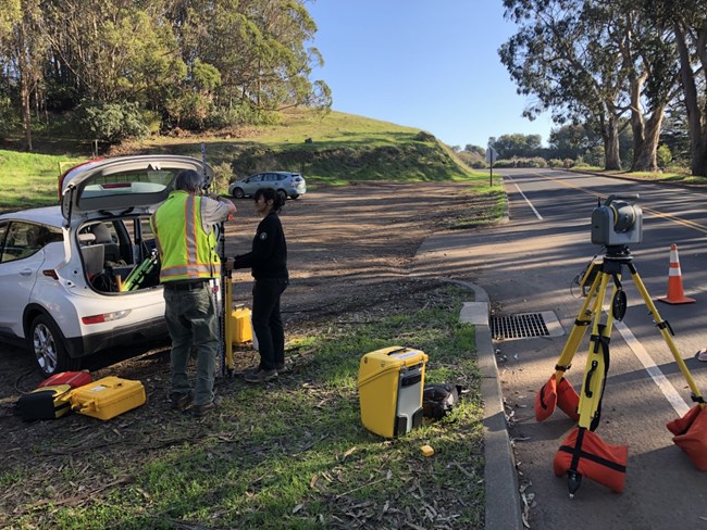 two people set up surveying equipment for mapping trees