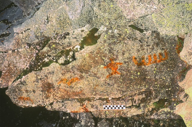 Orange colored pictographs on a rock Orange colored pictographs on a rock