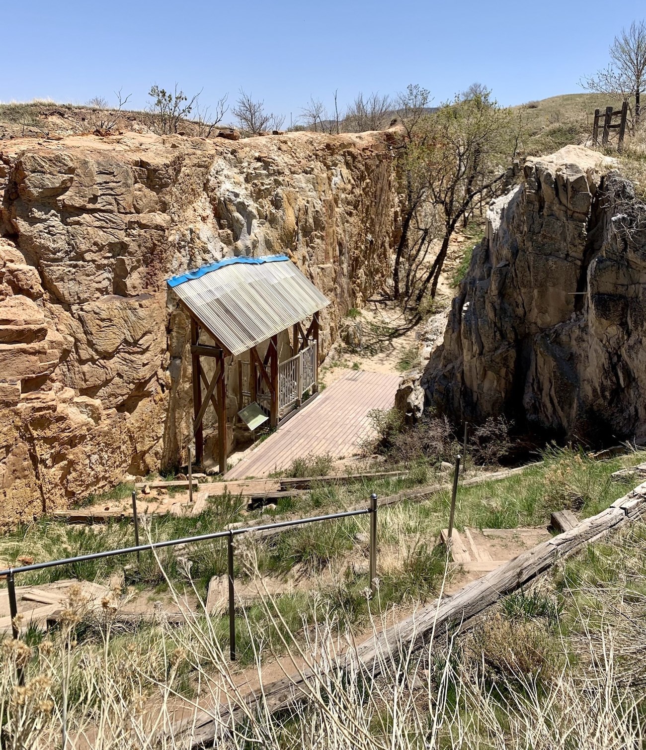 Photo of a fossil shelter along a trail. The trail is between two tall fins of sandstone.