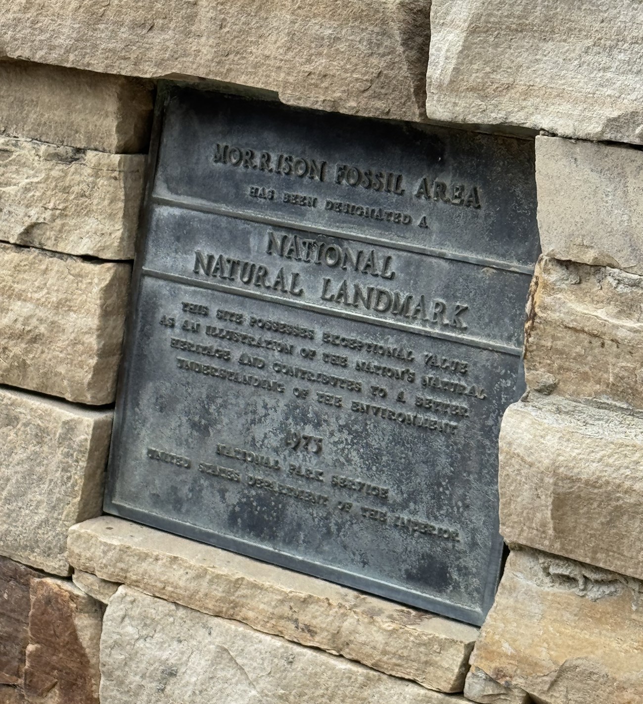 Photograph of bronze NNL plaque set among sandstone blocks. Text of the plaque is below the caption.