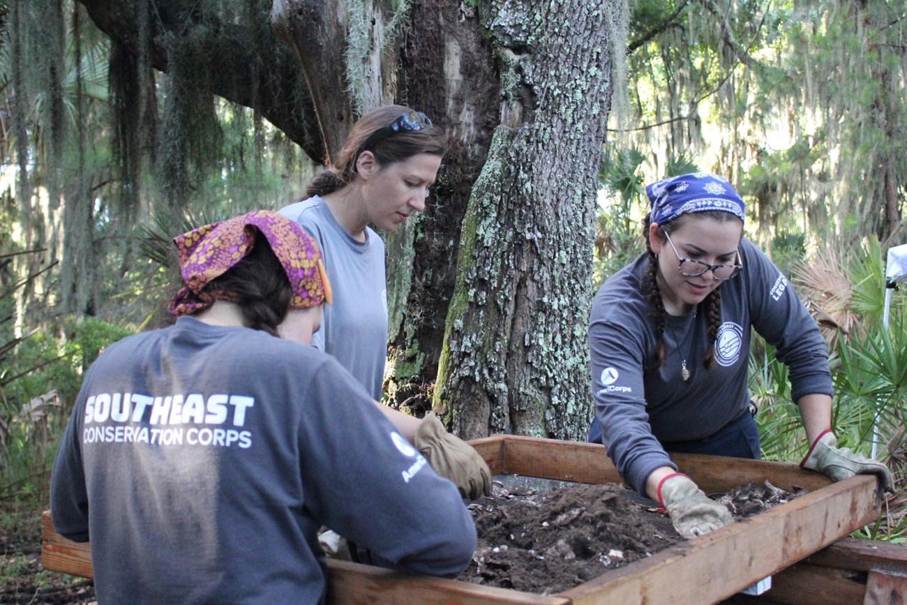 Three people at a sifting screen.