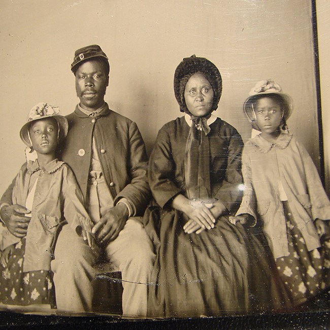 An African American soldier in Union Army uniform seated with his family. An African American solider in Union Army uniform seated with his family