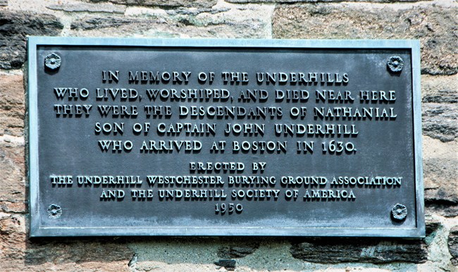 Metal plaque, with inscription, attached to a stone wall