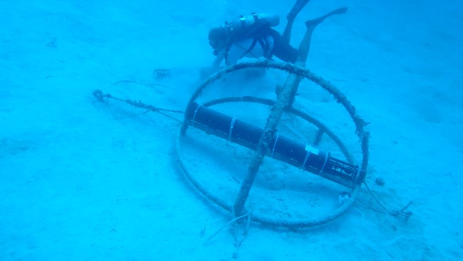 A diver works next to underwater acoustic monitoring equipment on the ocean floor at Buck Island Reef National Monument.