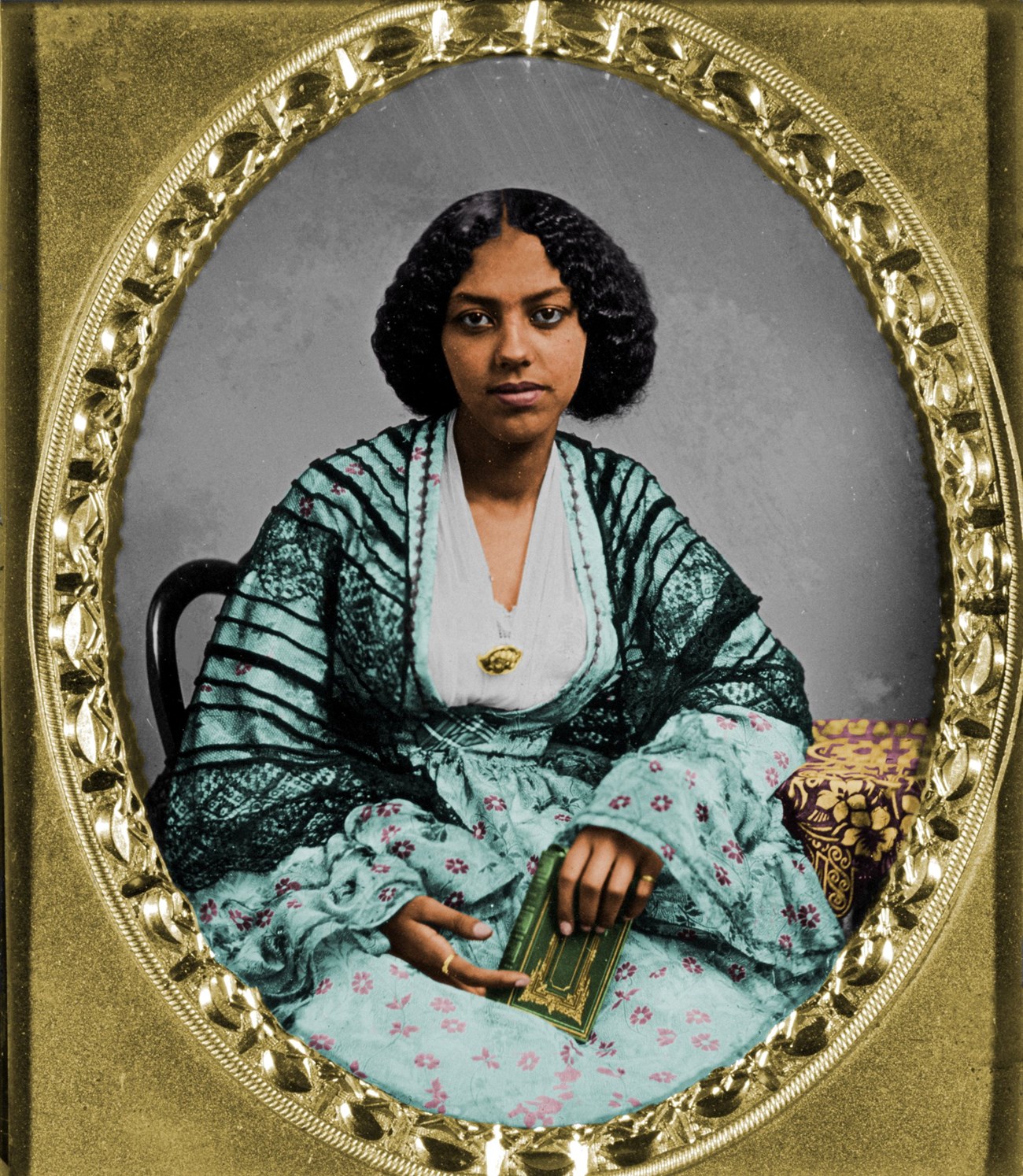 Colorized 1850s photo of an African American woman wearing bright blue dress and holding a green book.