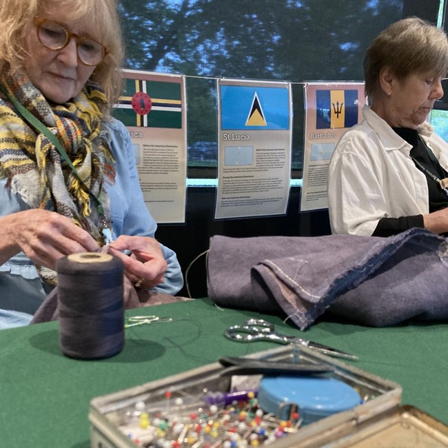 A Tailoring Brigade volunteer is shown working on a sewing project.