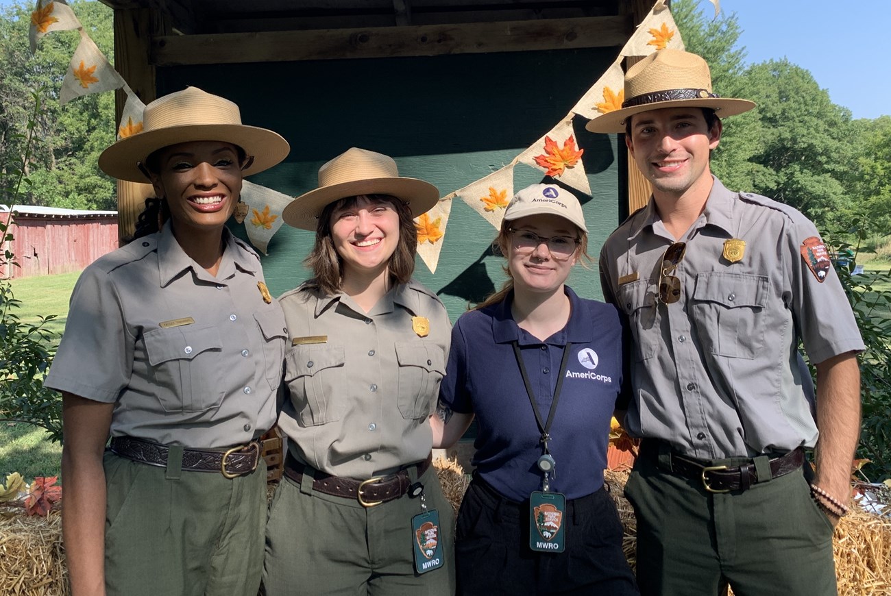 three people in park ranger uniforms and a person in an AmeriCorps shirt