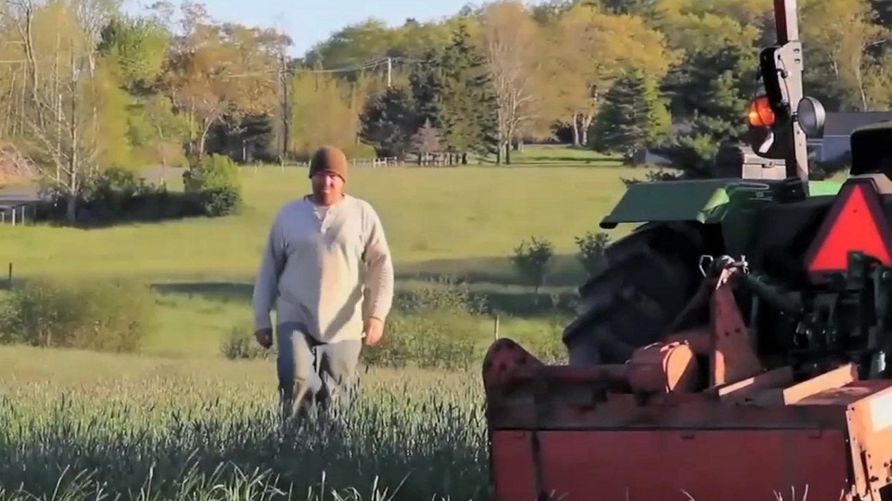 Man walks through field approaching a tractor