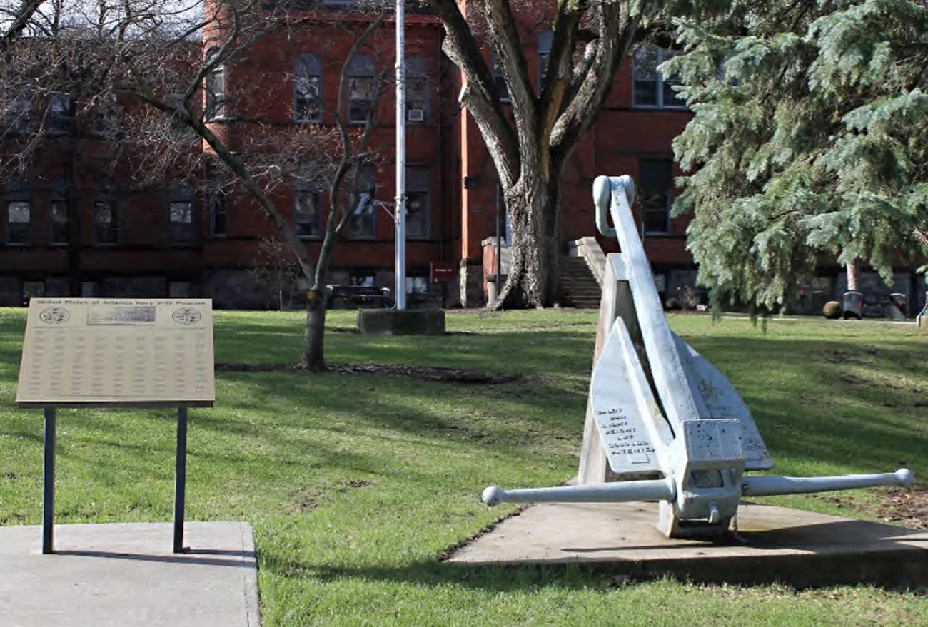 image of navy ship anchor and memorial plaque with names on a grassy lawn
