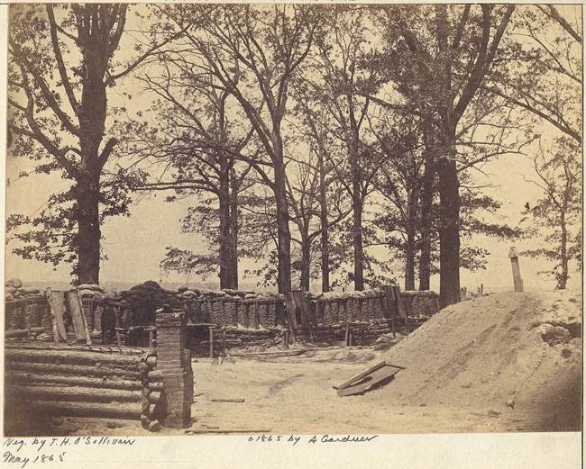 Fort Stedman, Virginia Black and white image of trees with a large dirt pile on the right, and a small wood and stone wall