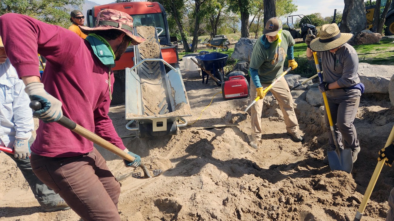 Volunteers in Merritt Park Group of people shoveling sand onto conveyor belt