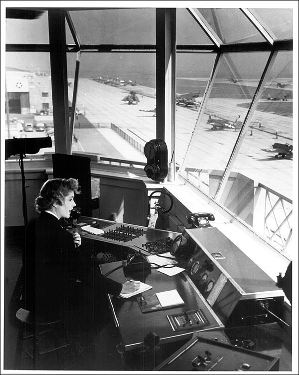 lt= Woman sitting at a table with many dials