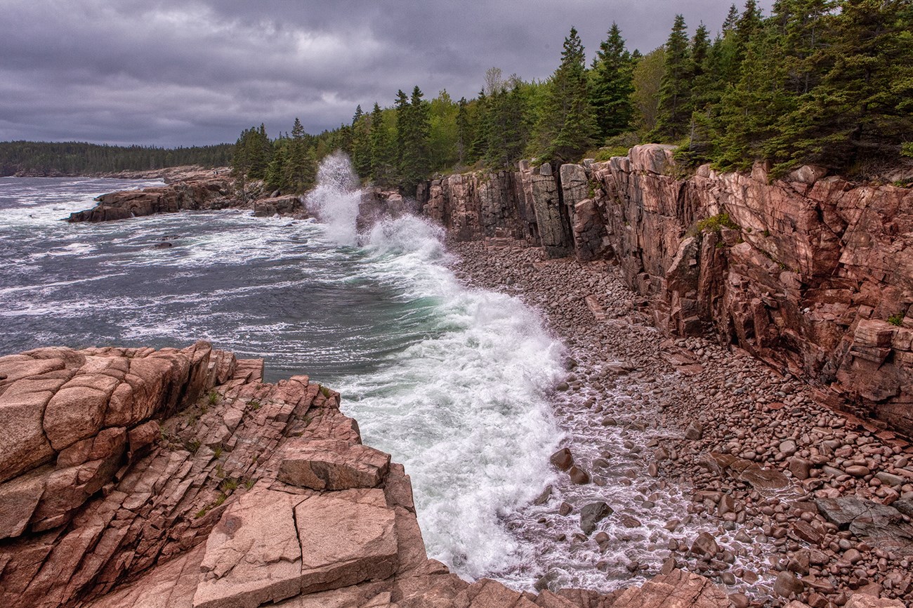 Waves crashing against high rocks and wooded coastline Waves crashing against high rocks and wooded coastline
