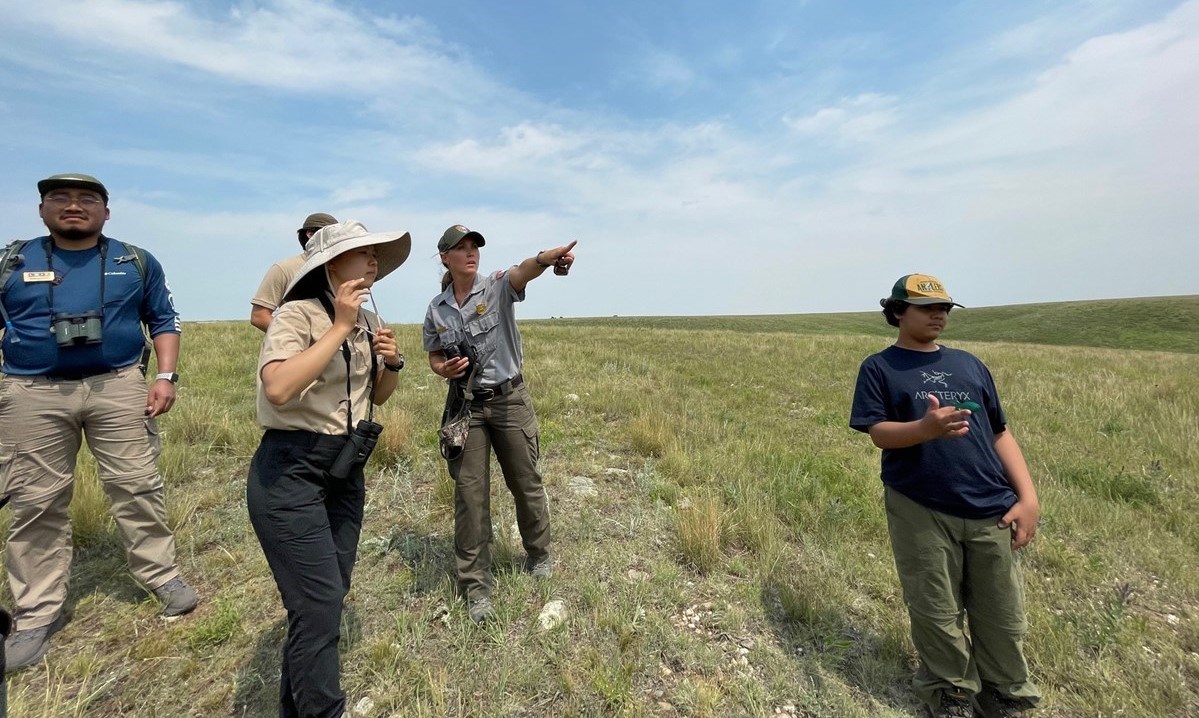 Ranger pointing at something off camera for a group of interns