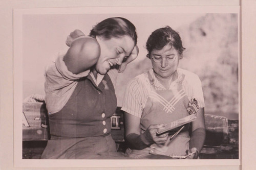 Elzada Clover and Lois Jotter sit next to each other looking at a book.