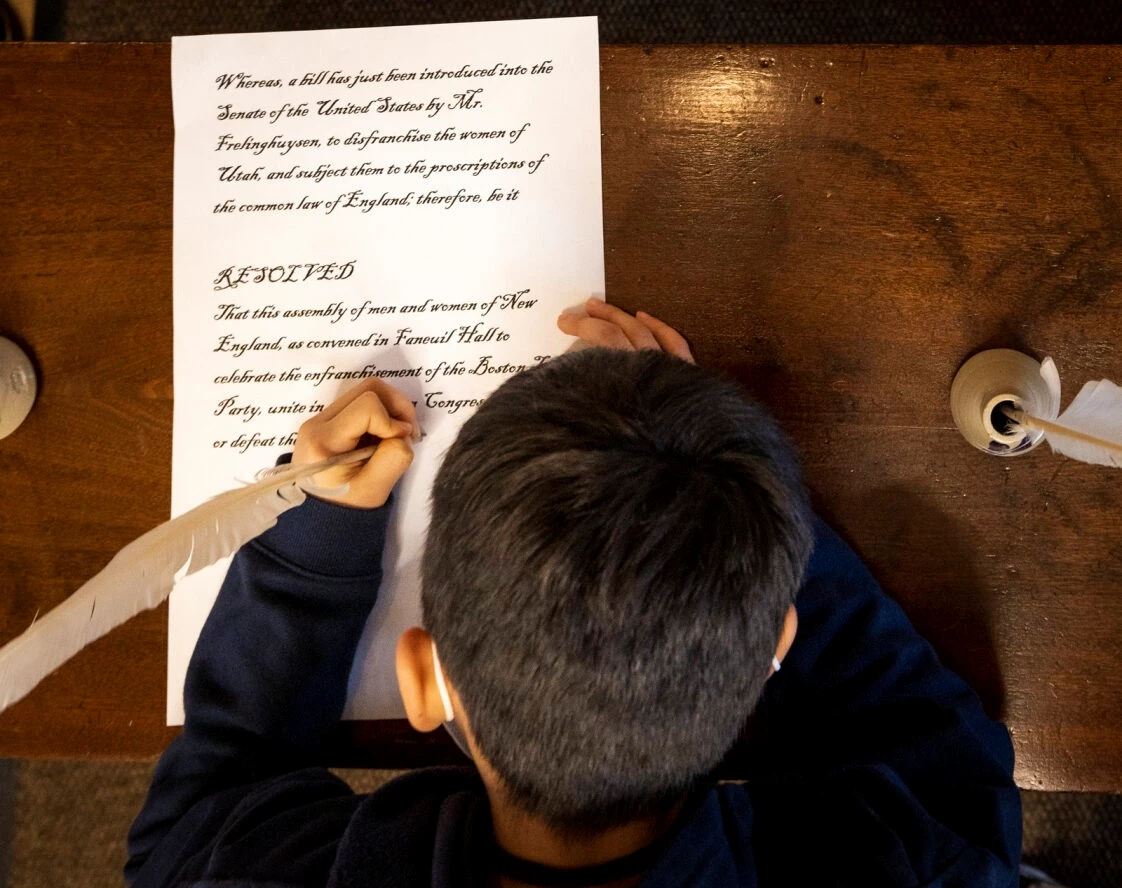 Woman's Tea Party signing A child signing a document with a quill pen