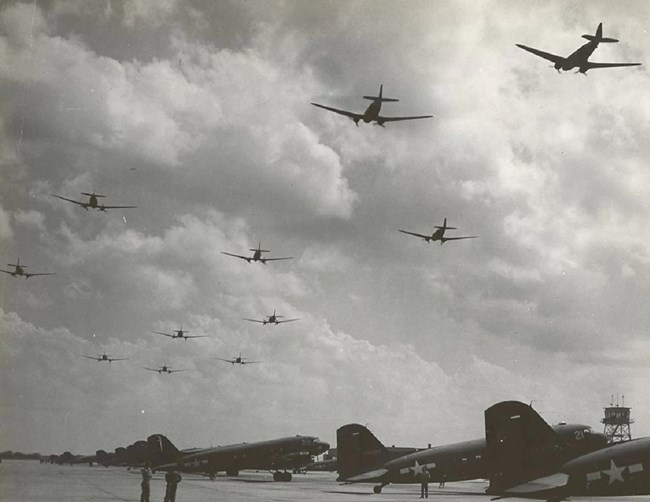 lt= large military prop planes lined up on a tarmac during WW2