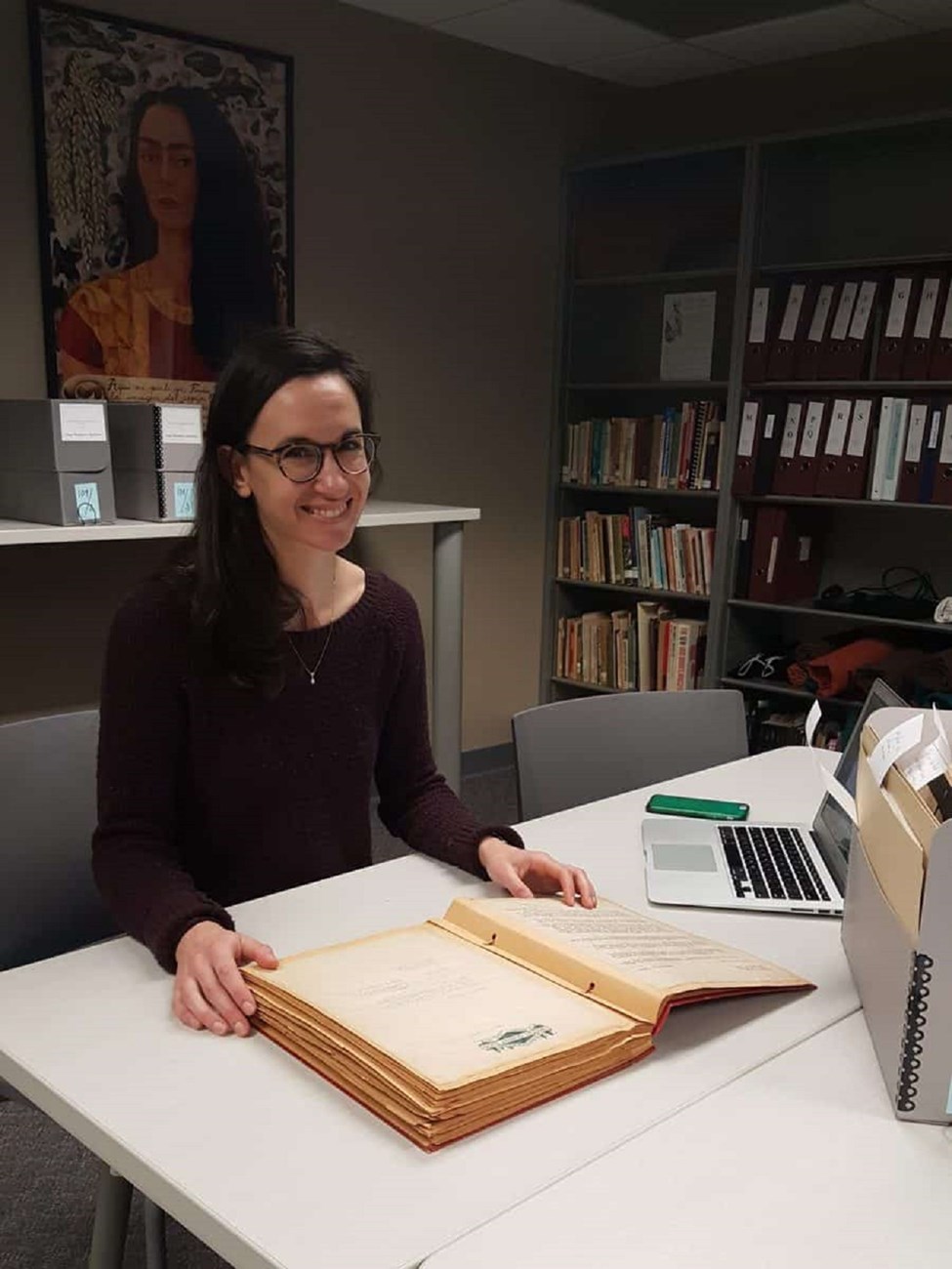 Ella conducting archival research in the Iowa Women’s Archives, 2019. Ella conducting archival research in the Iowa Women’s Archives sitting in a desk with a very large book.