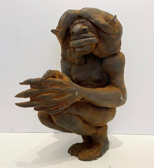 A cast iron goblin-like mystical creature in a crouching position