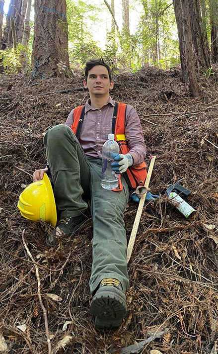 William Weinberg man sits on forest floor with scientific equipment around him