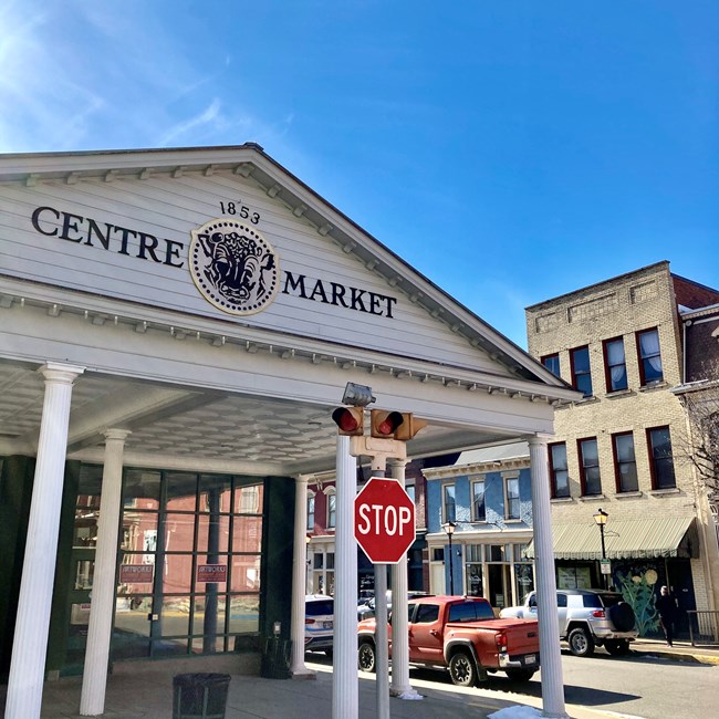 Wheeling Centre Market Front of white, columned entrance to building with front portico sign reading "Centre Market" with a seal in between the words and date '1853'. At right, city street with brick buildings.