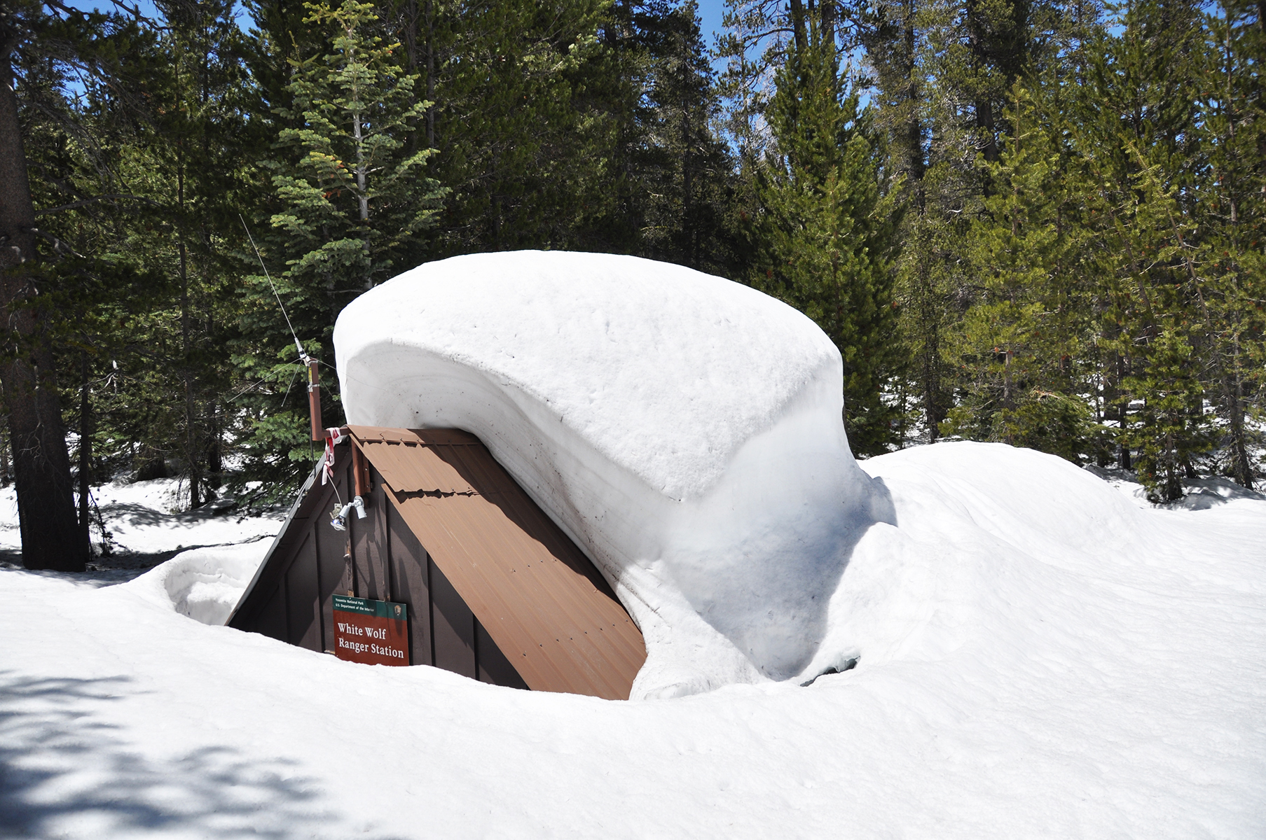 The uppermost rooftop of a ranger station in Yosemite National Park is all that's visible above deep snow, May 2023.