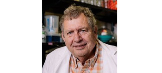 Headshot of man with light brown hair in white lab coat.