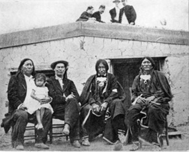 1869 period photo at Fort Dodge, KS Photo of Arapaho Chief Little Raven sitting next to William Bent with two sons and granddaughter in front of adobe structure