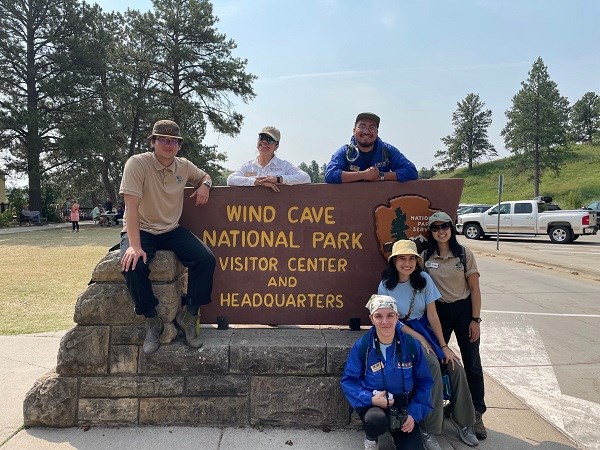 Wind cave Trip five people posing in front of the Wind Cave National Park sign