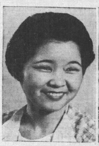 Winifred-Tada-Feb 1940 A dark haired woman smiles facing the camera. She wears a checkered shirt with a white collar.