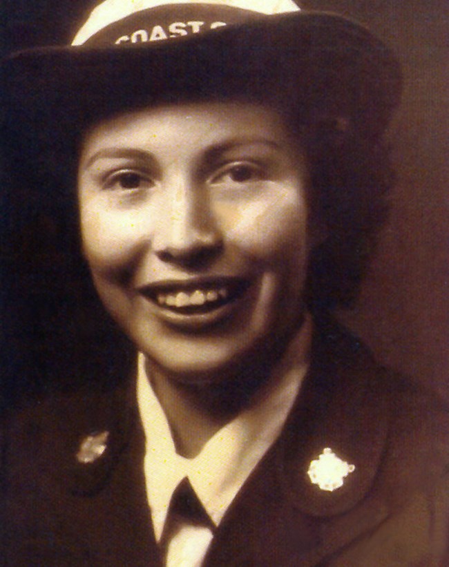 Mildren Cleghorn Womack, Courtesy of Women's Military Memorial Sepia picture of a smiling woman in a dark uniform and a Coast Guard cap