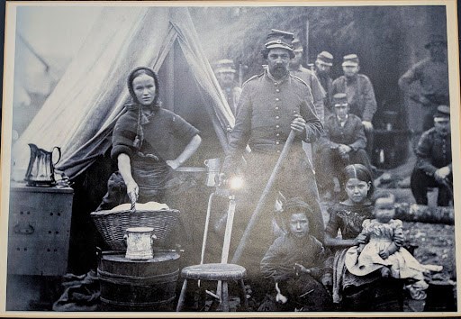 Women at Fort Laramie An old family photograph showing parents and children standing together in front of a camping tent.