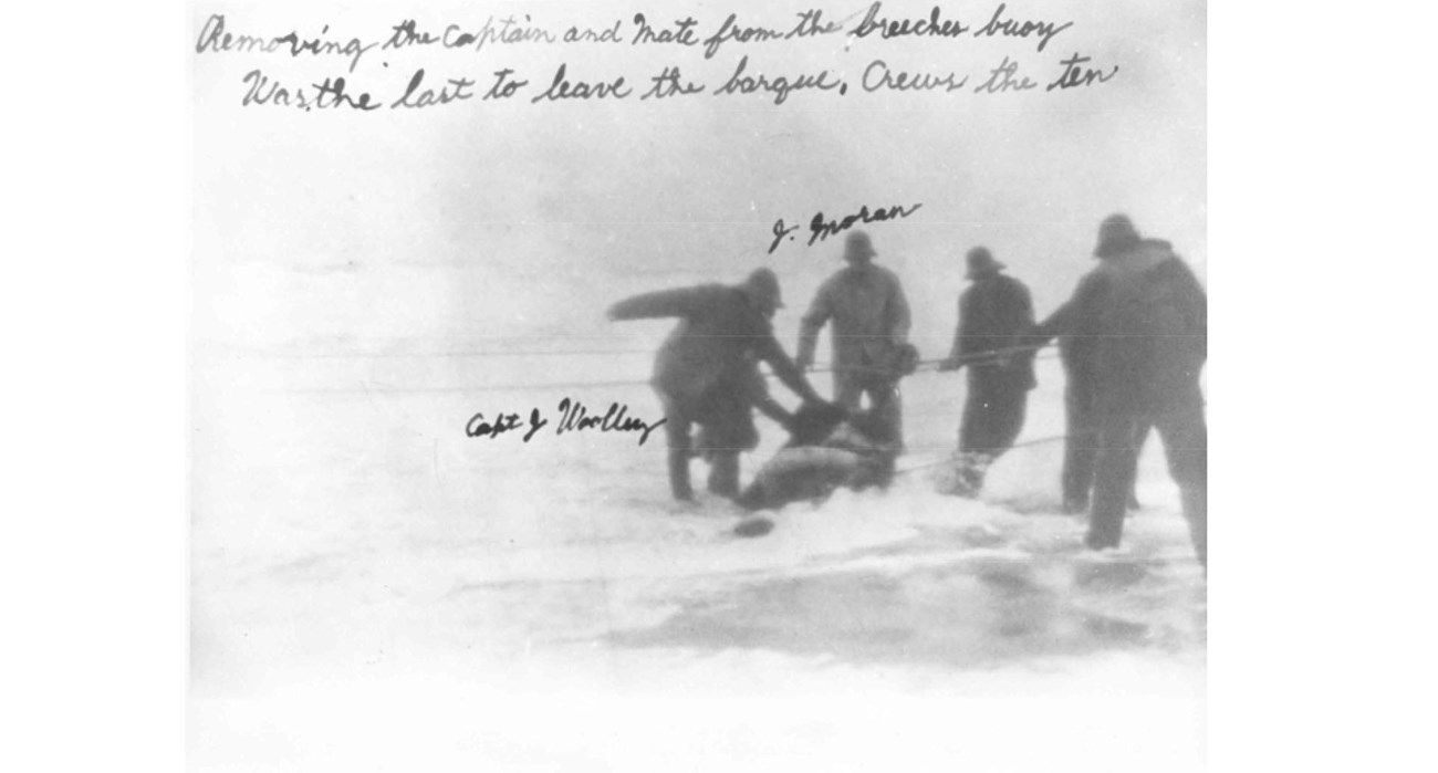 Wreck of the Phinney four men pull a large object onto the shore