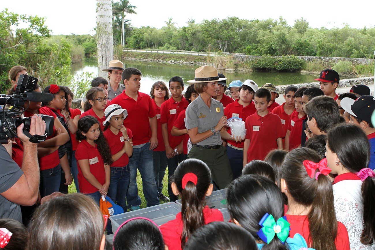 Yvette Cano talking to a large group of kids while being filmed