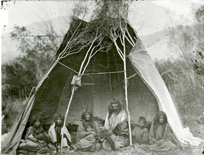 Black and white photo of a group of Tukudika men women and children sitting.