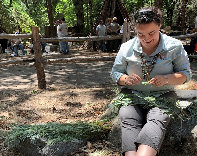 Ranger Emily Dayhoff sitting while cleaning a basket in her lap