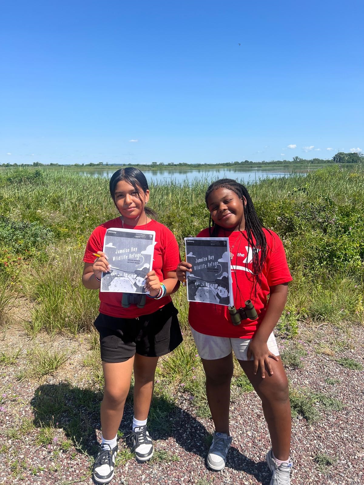 Young campers at Jamaica Bay Wildlife Refuge Two young campers in front a body of water with papers in hand